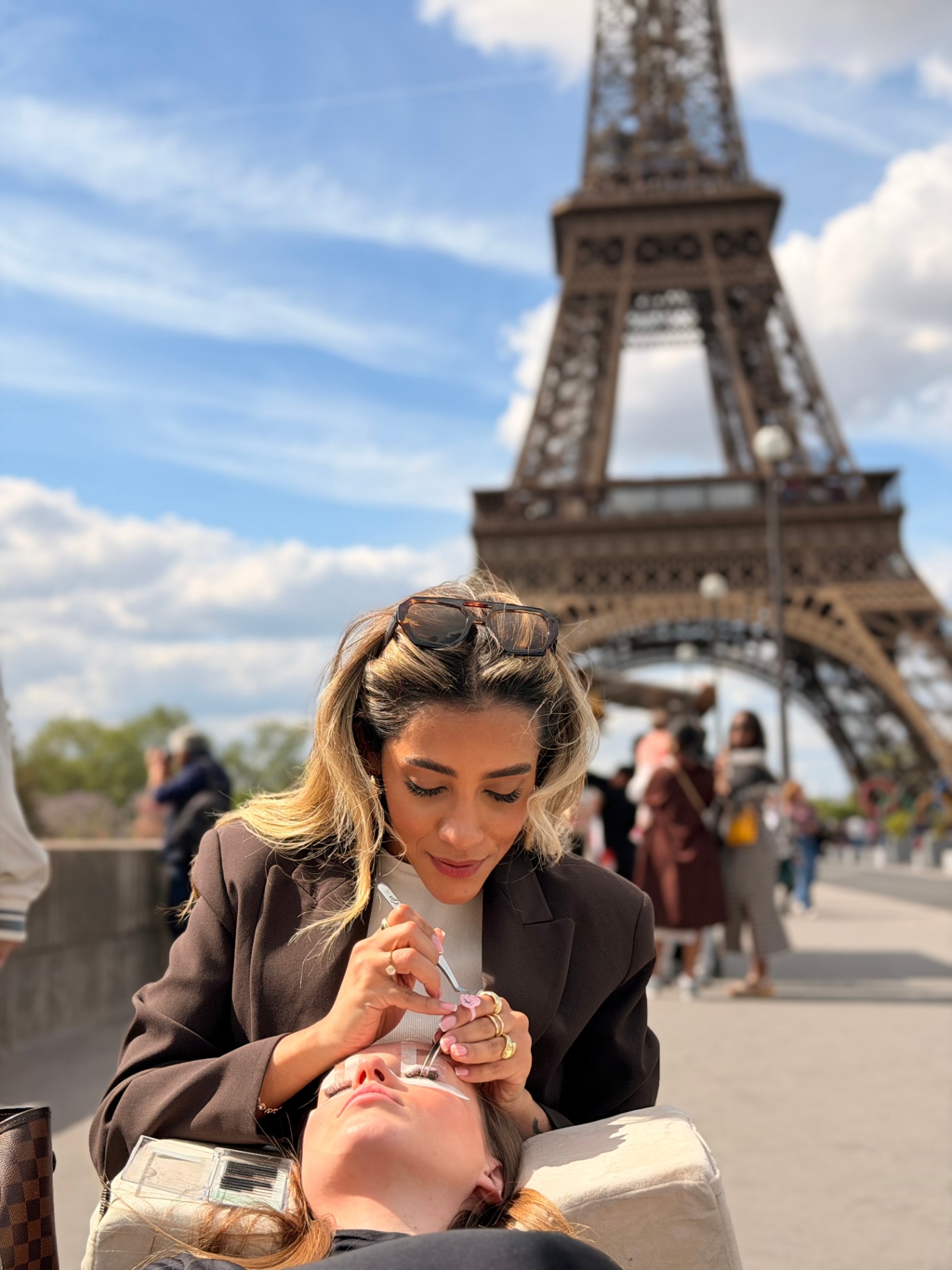 Camilla Coimbra réalisant une extension de cils devant la Tour Eiffel
